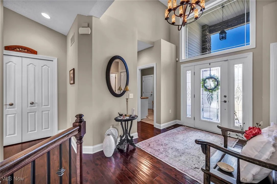 Foyer featuring a high ceiling, dark wood-type flooring, and a chandelier