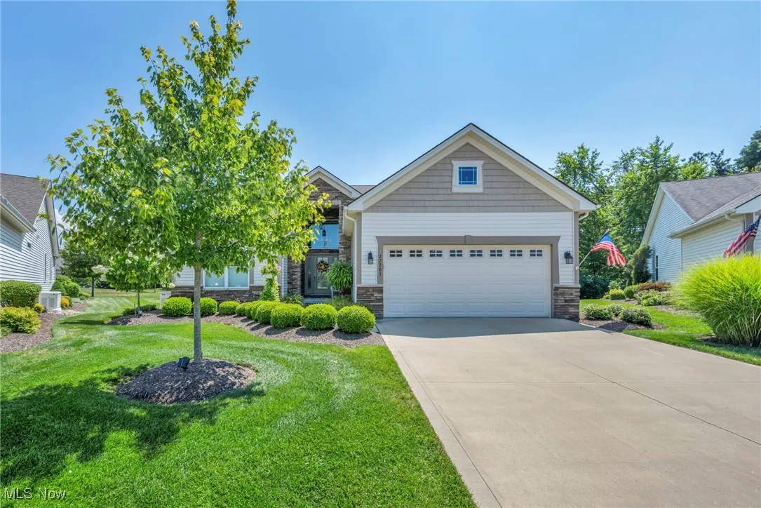 Craftsman inspired home featuring driveway, stone siding, a front lawn, and a garage