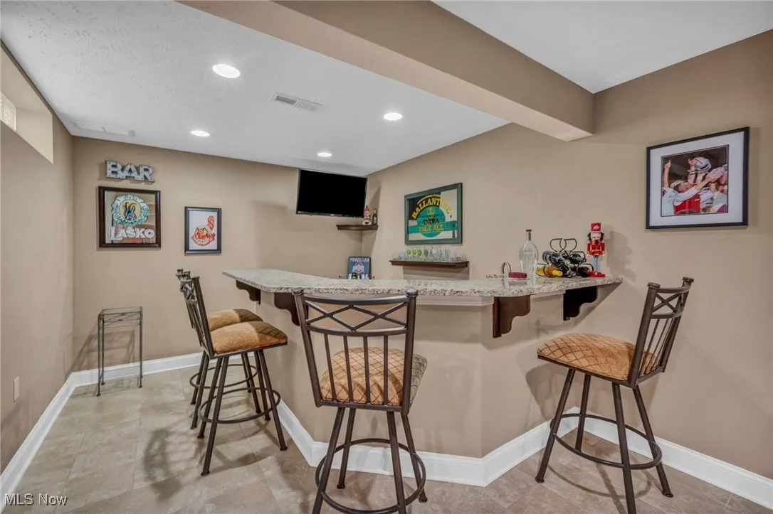 Indoor dry bar featuring light granite countertops and recessed lighting