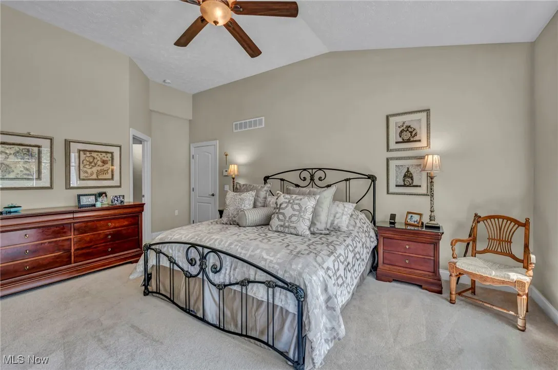 Carpeted bedroom featuring lofted ceiling, a ceiling fan, and a textured ceiling