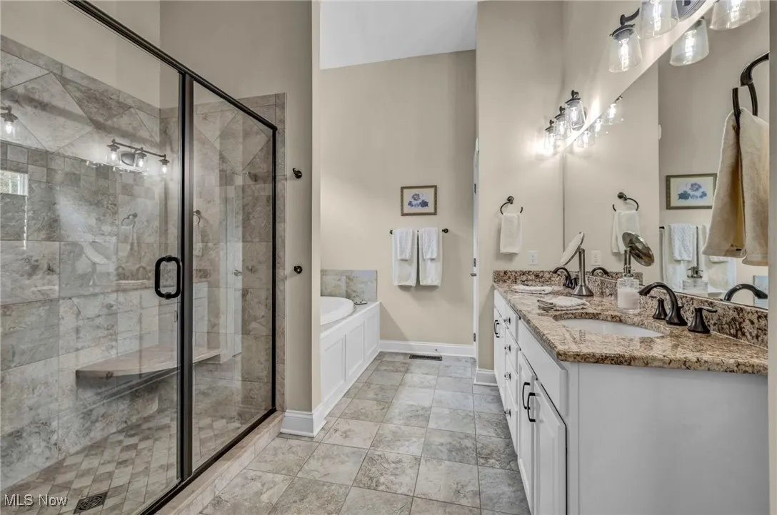 Bathroom with a bath, a stall shower, double vanity, and light tile patterned floors