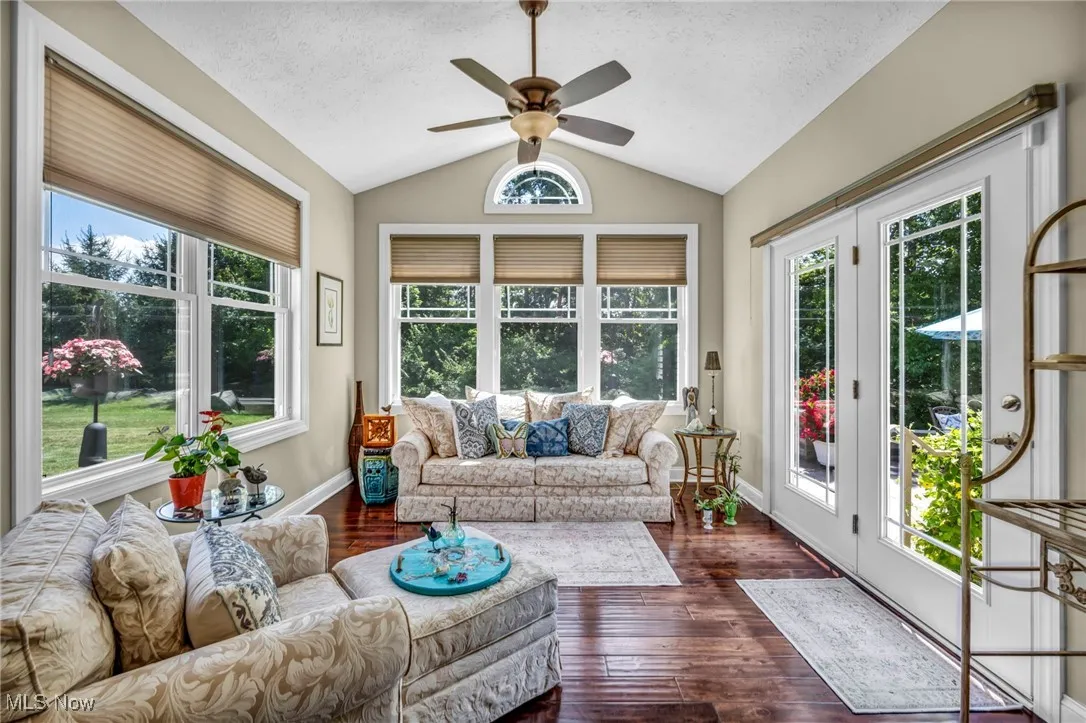 Sunroom / solarium with vaulted ceiling, hardwood / wood-style flooring, french doors, and a textured ceiling