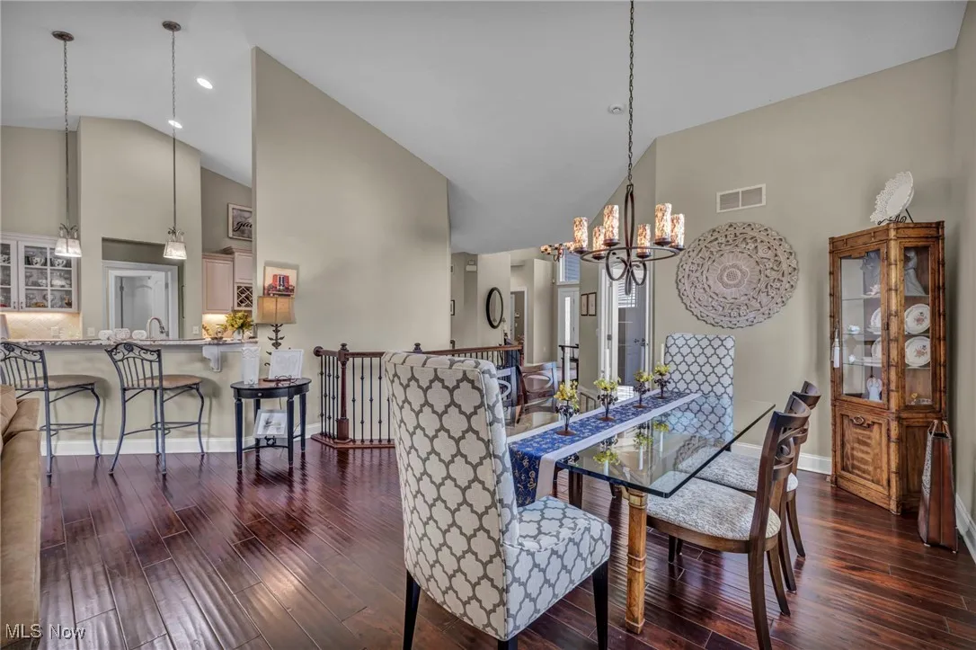 Dining space featuring high vaulted ceiling, dark wood-type flooring, and a chandelier