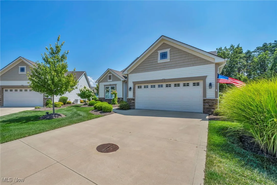 View of front of property featuring stone siding, driveway, an attached garage, and a front yard
