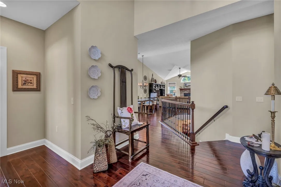 Hallway with an upstairs landing, dark wood-style flooring, lofted ceiling, and a​​‌​​​​‌​​‌‌​‌‌​​​‌‌​‌​‌​‌​​​‌​​ chandelier