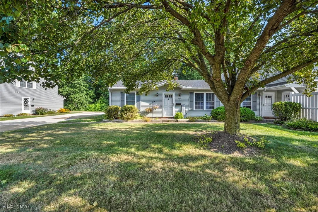 View of property hidden behind natural elements featuring a front yard