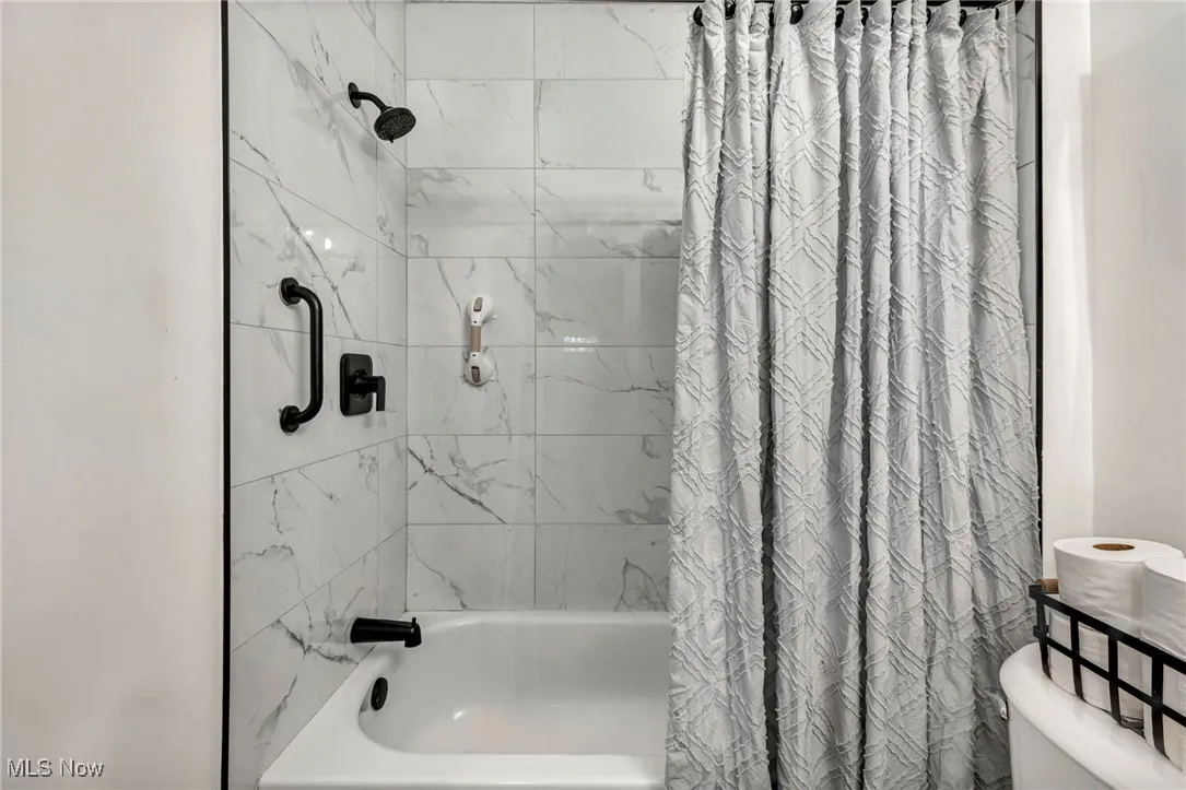 Full bath featuring shower / bath combo with shower curtain and toilet