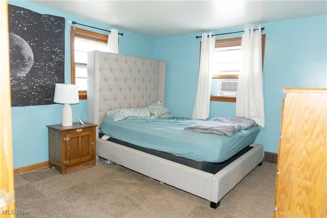 Carpeted bedroom with baseboards and cooling unit