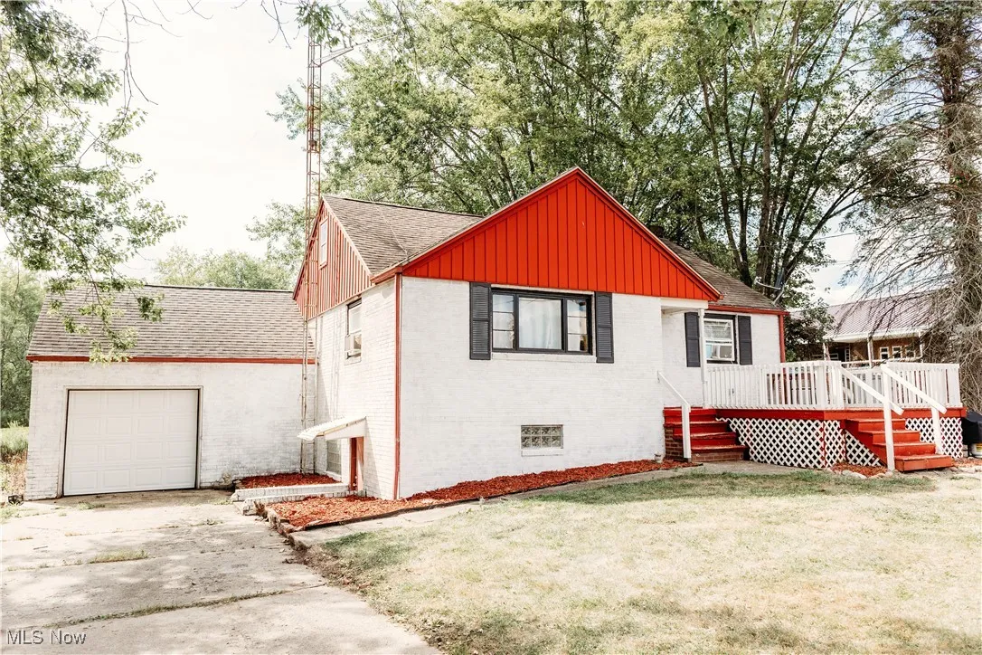 Back of property featuring brick siding, board and batten siding, roof with shingles, a yard, and an attached garage