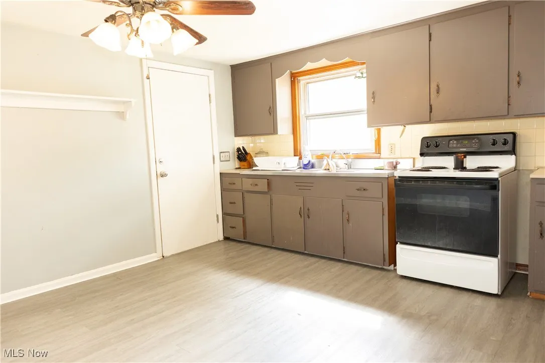 Kitchen featuring tasteful backsplash, electric stove, light countertops, a ceiling fan, and light wood-type flooring
