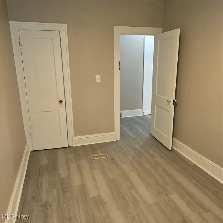 Alt shot. Empty room featuring baseboards, wood finished floors, and visible vents