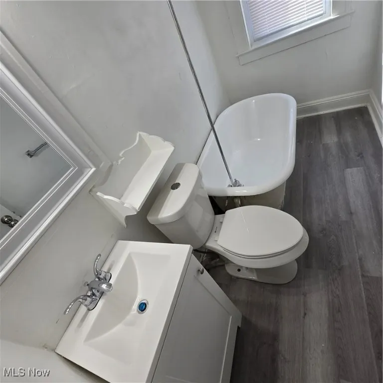 Bathroom with wood finished floors, vanity, toilet, and baseboards