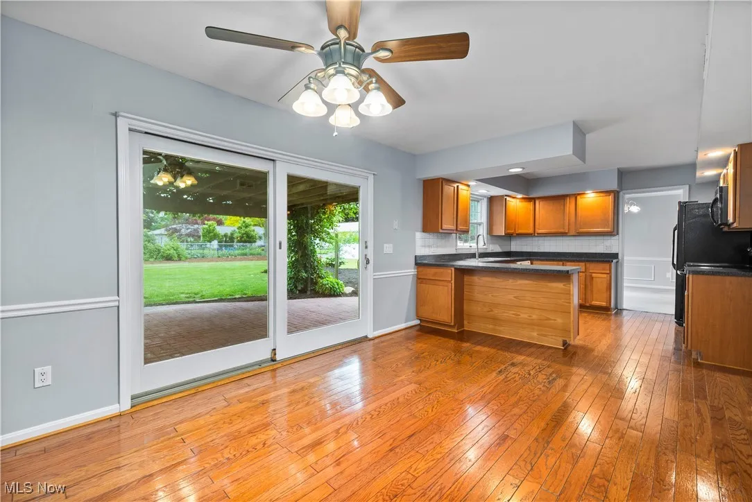 Kitchen with dark countertops, brown cabinets, hardwood / wood-style flooring, ceiling fan, and a peninsula