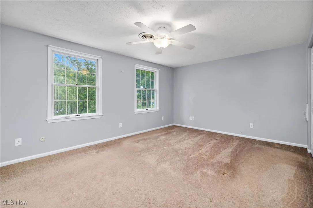 Carpeted empty room featuring ceiling fan and a textured ceiling