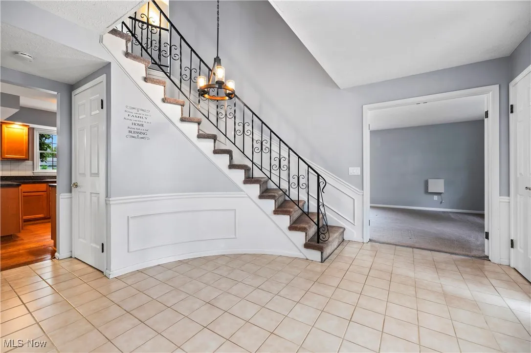 Stairs featuring a wainscoted wall, tile patterned flooring, a decorative wall, and carpet floors
