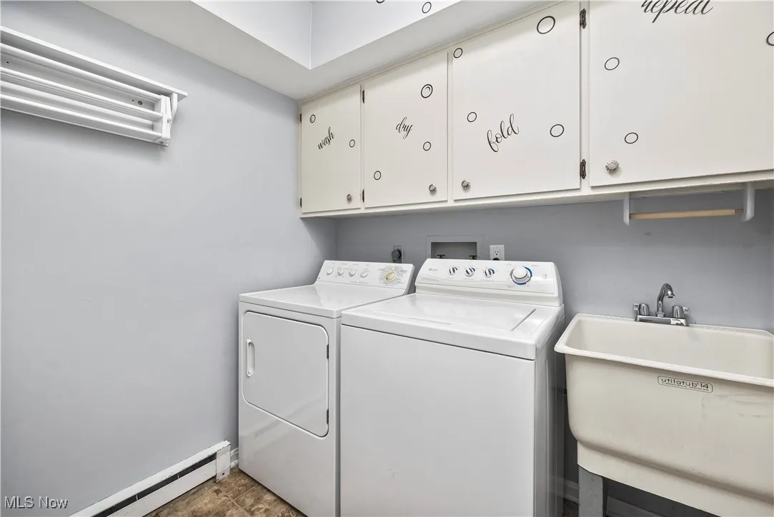 Laundry area featuring cabinet space, washer and dryer, and a baseboard heating unit