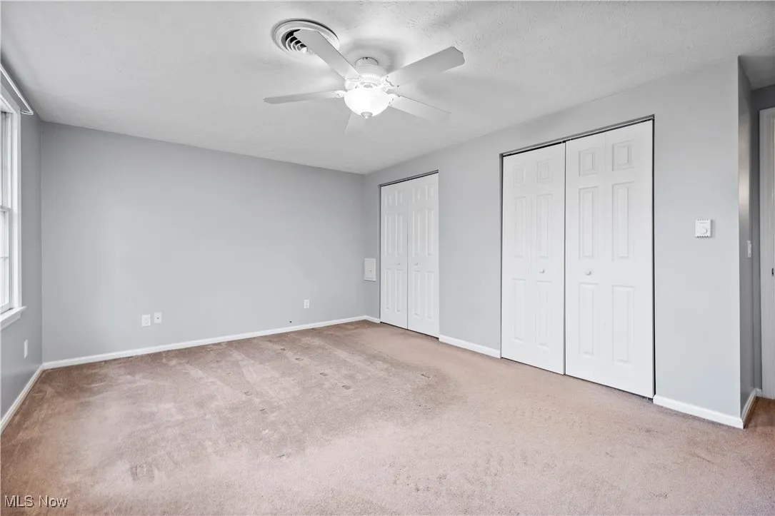 Unfurnished bedroom featuring two closets, carpet floors, and a ceiling fan
