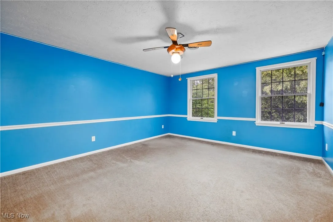 Spare room with ceiling fan, plenty of natural light, carpet, and a textured ceiling