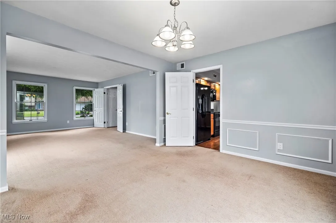 Spare room with carpet flooring and a chandelier