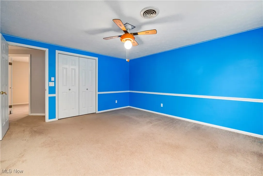 Unfurnished bedroom featuring carpet flooring, a closet, and a ceiling fan