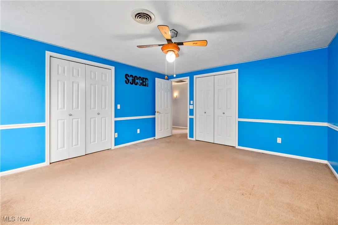 Unfurnished bedroom featuring two closets, carpet, and ceiling fan