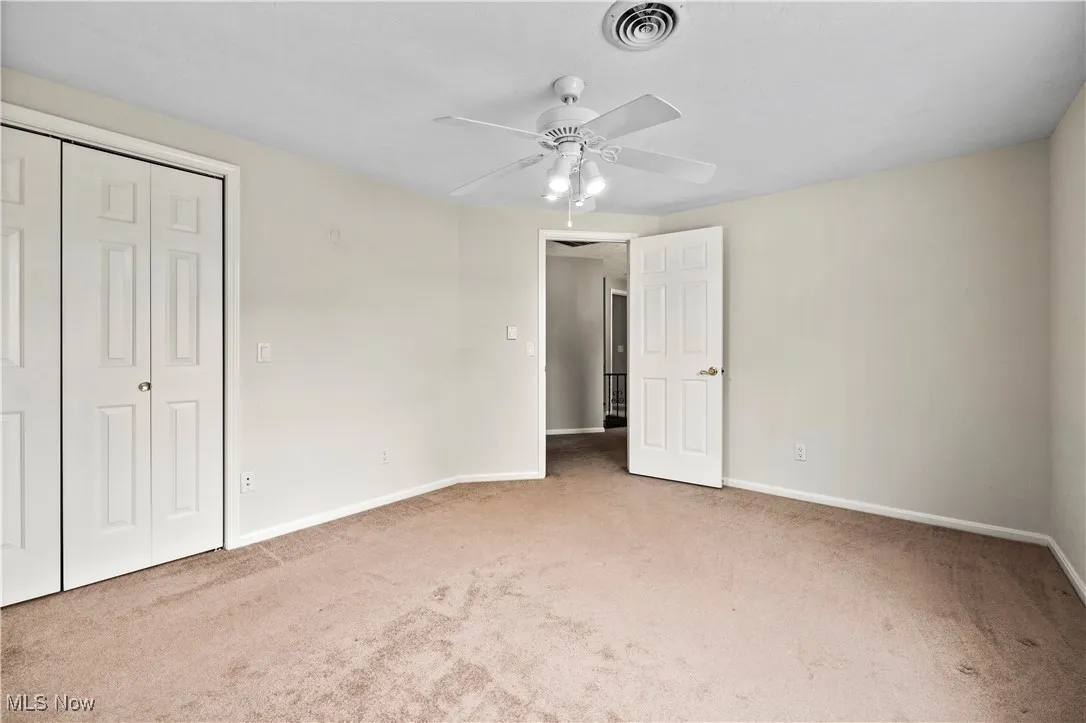 Unfurnished bedroom with carpet, a closet, and a ceiling fan