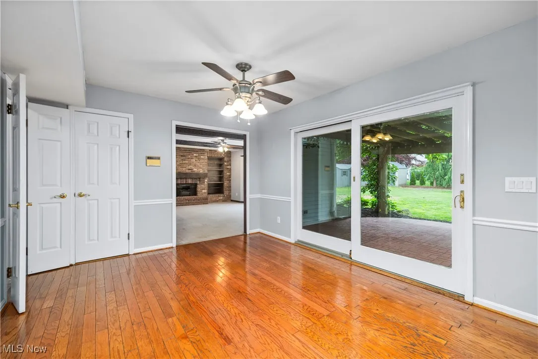 Empty room featuring ceiling fan, hardwood / wood-style floors, and a brick fireplace