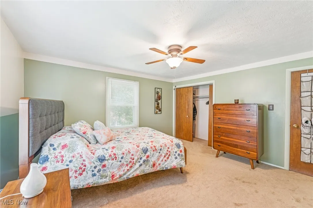 Carpeted bedroom featuring a ceiling fan, a closet, and a textured ceiling