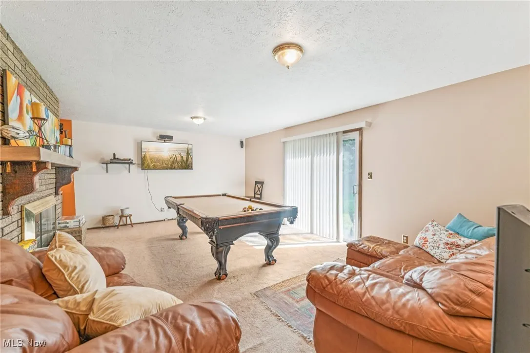 Playroom with a fireplace, carpet, pool table, and a textured ceiling