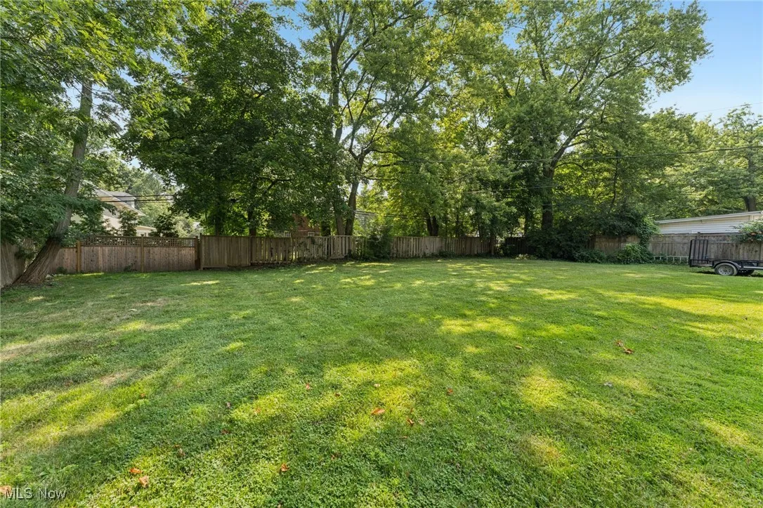 Fenced backyard with view of scattered trees