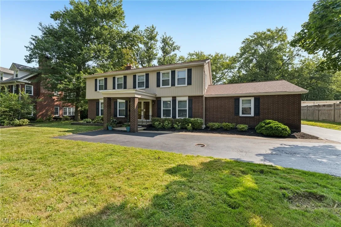 Colonial home with brick siding, asphalt driveway, and a chimney