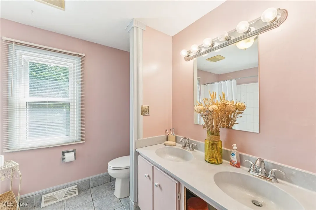 Bathroom with light tile patterned floors, double vanity, and curtained shower