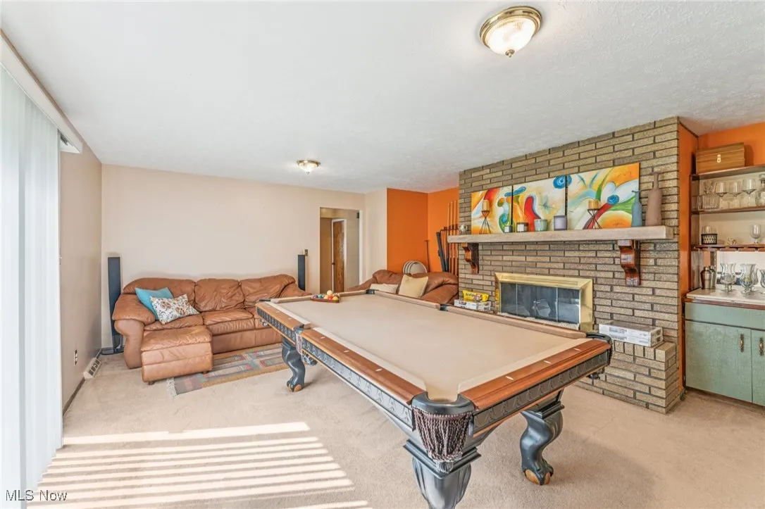 Game room featuring pool table, light carpet, and a brick fireplace