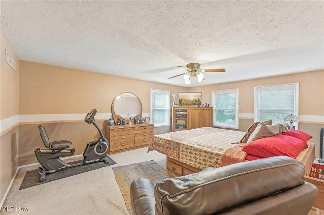 Carpeted bedroom featuring a textured ceiling and a ceiling fan