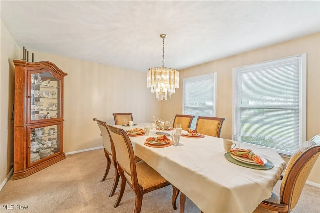 Dining space featuring light colored carpet and a​​‌​​​​‌​​‌‌​‌‌​​​‌‌​‌​‌​‌​​​‌​​ chandelier