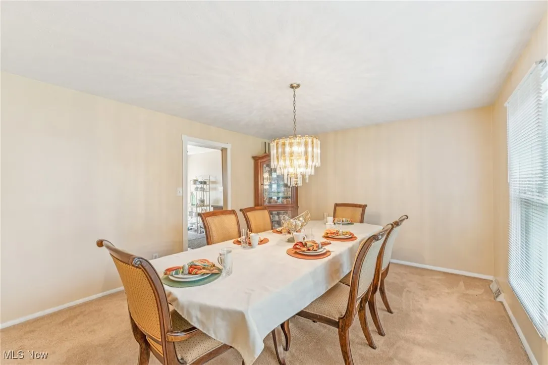 Dining space featuring light colored carpet and a chandelier