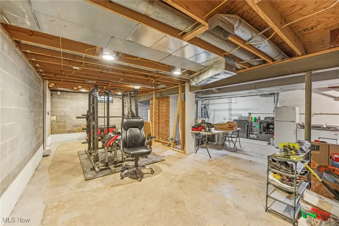 Unfinished basement featuring freestanding refrigerator