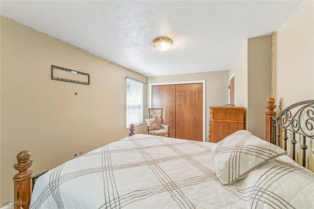 Bedroom with a textured ceiling and a closet
