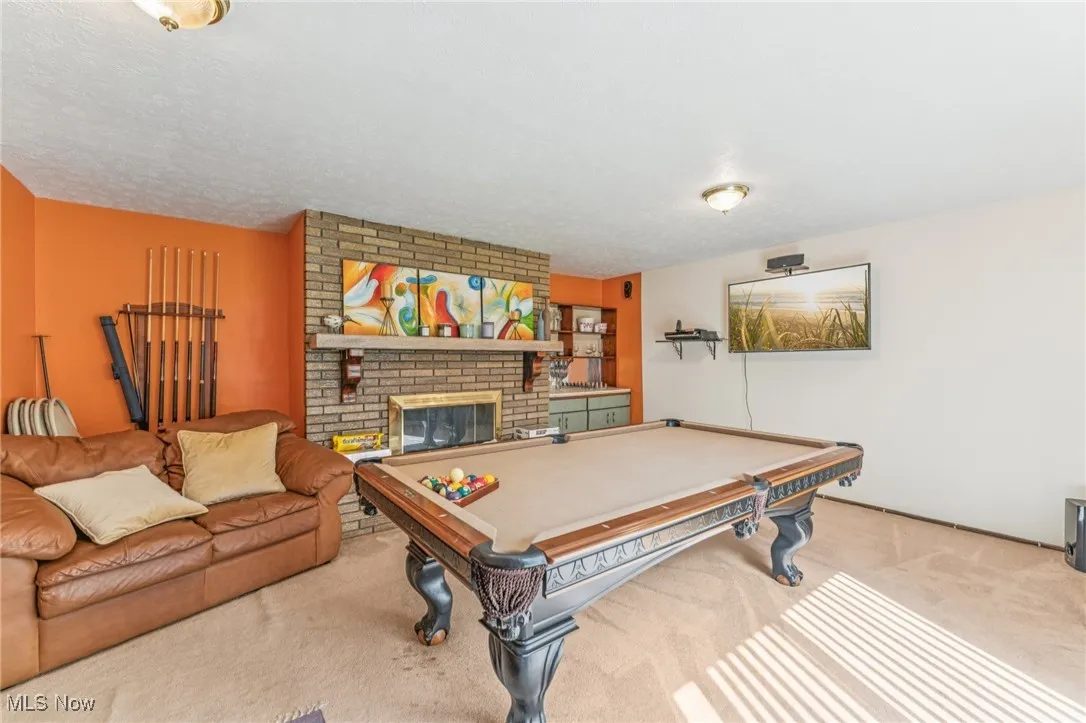 Recreation room with carpet flooring, billiards table, a brick fireplace, and a textured ceiling