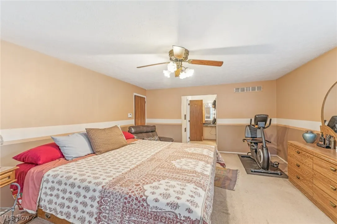 Carpeted bedroom with a ceiling fan and ensuite bathroom
