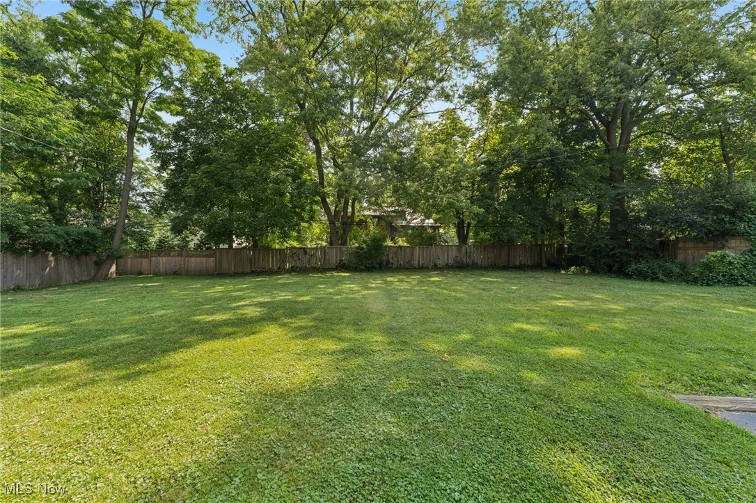 Fenced backyard featuring view of scattered trees
