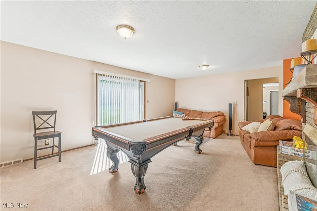 Game room with billiards table, light colored carpet, and a textured ceiling