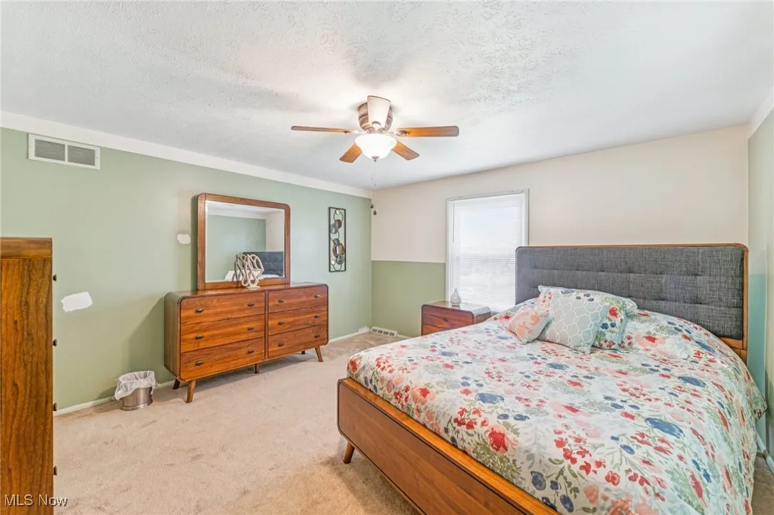 Carpeted bedroom with a textured ceiling and a ceiling fan