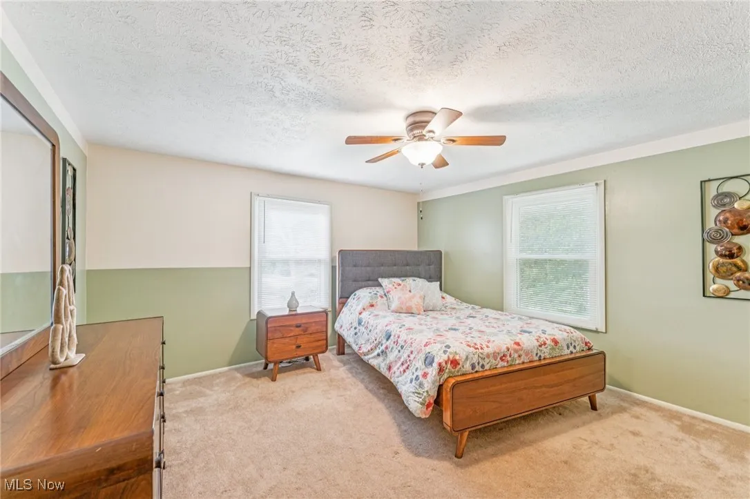 Carpeted bedroom with a textured ceiling and ceiling fan