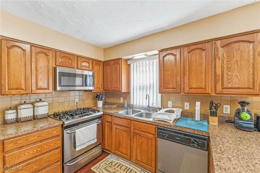 Kitchen with appliances with stainless steel finishes, backsplash, and brown cabinetry