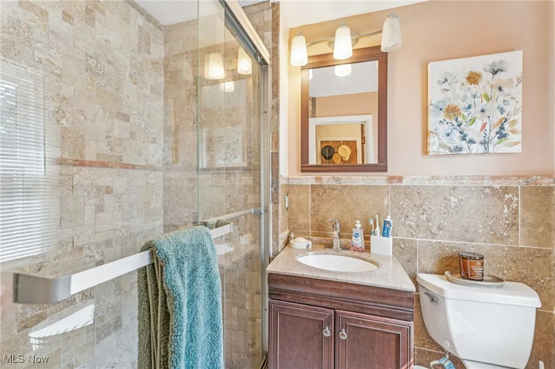Full bath featuring tile walls, vanity, and a stall shower
