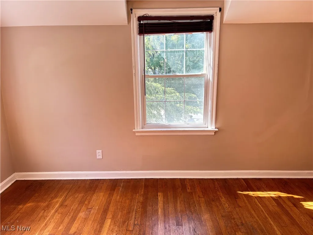 Unfurnished room with baseboards and hardwood / wood-style flooring