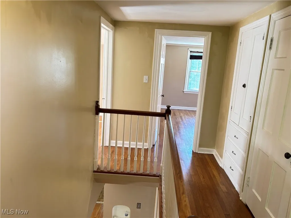 Hall featuring dark wood-style floors and an upstairs landing