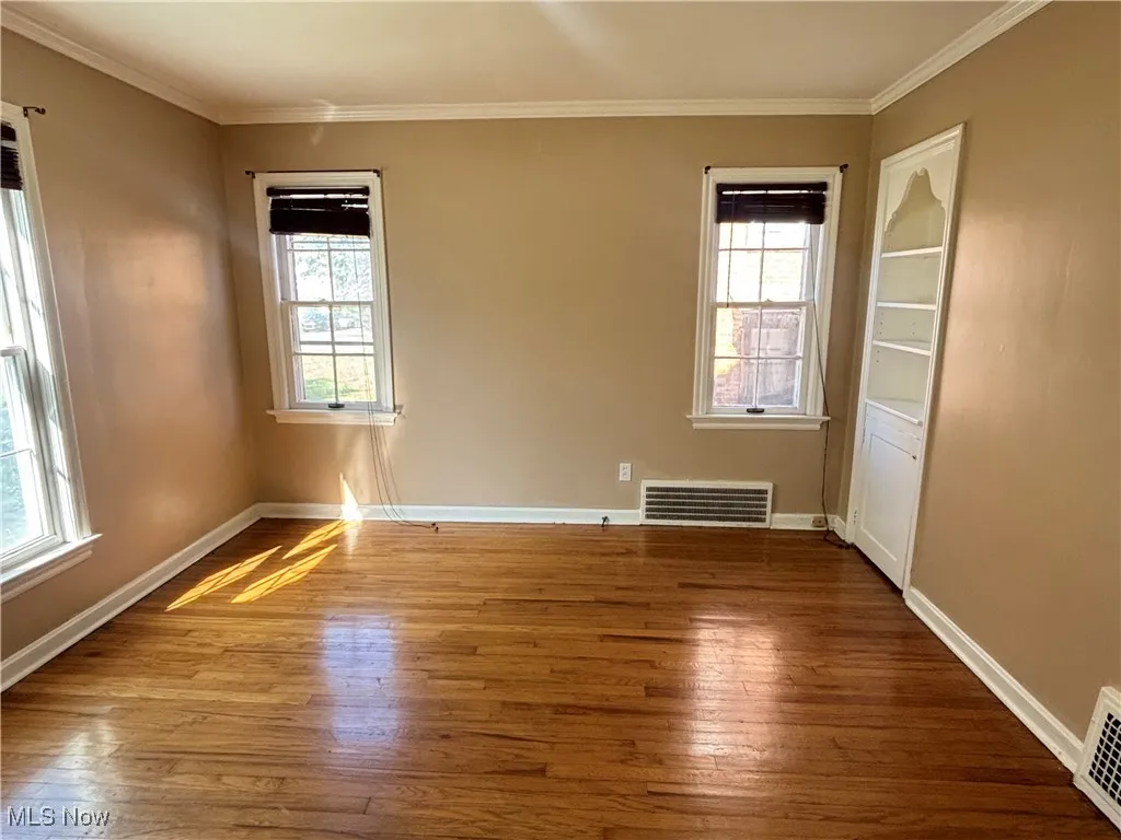 Empty room featuring crown molding and wood-type flooring