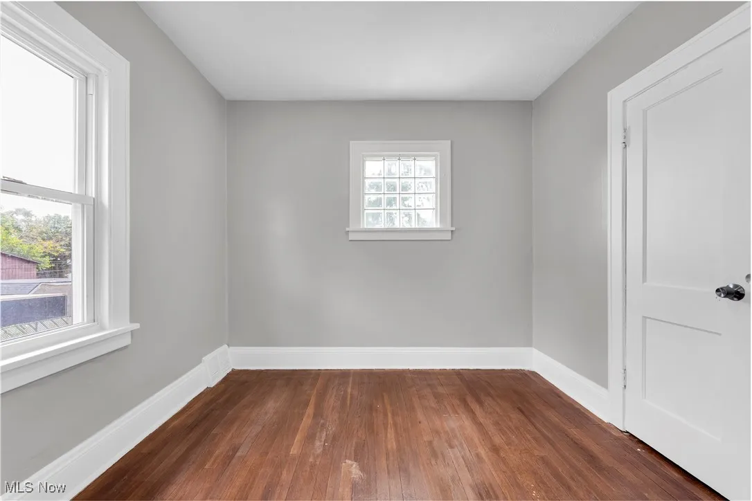 Unfurnished room featuring dark wood-style flooring and baseboards